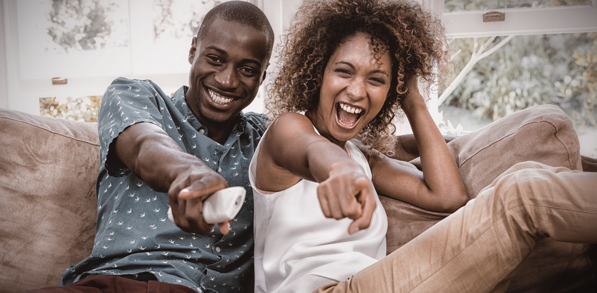 Happy young couple watching television in living room Happy young couple watching television in living room